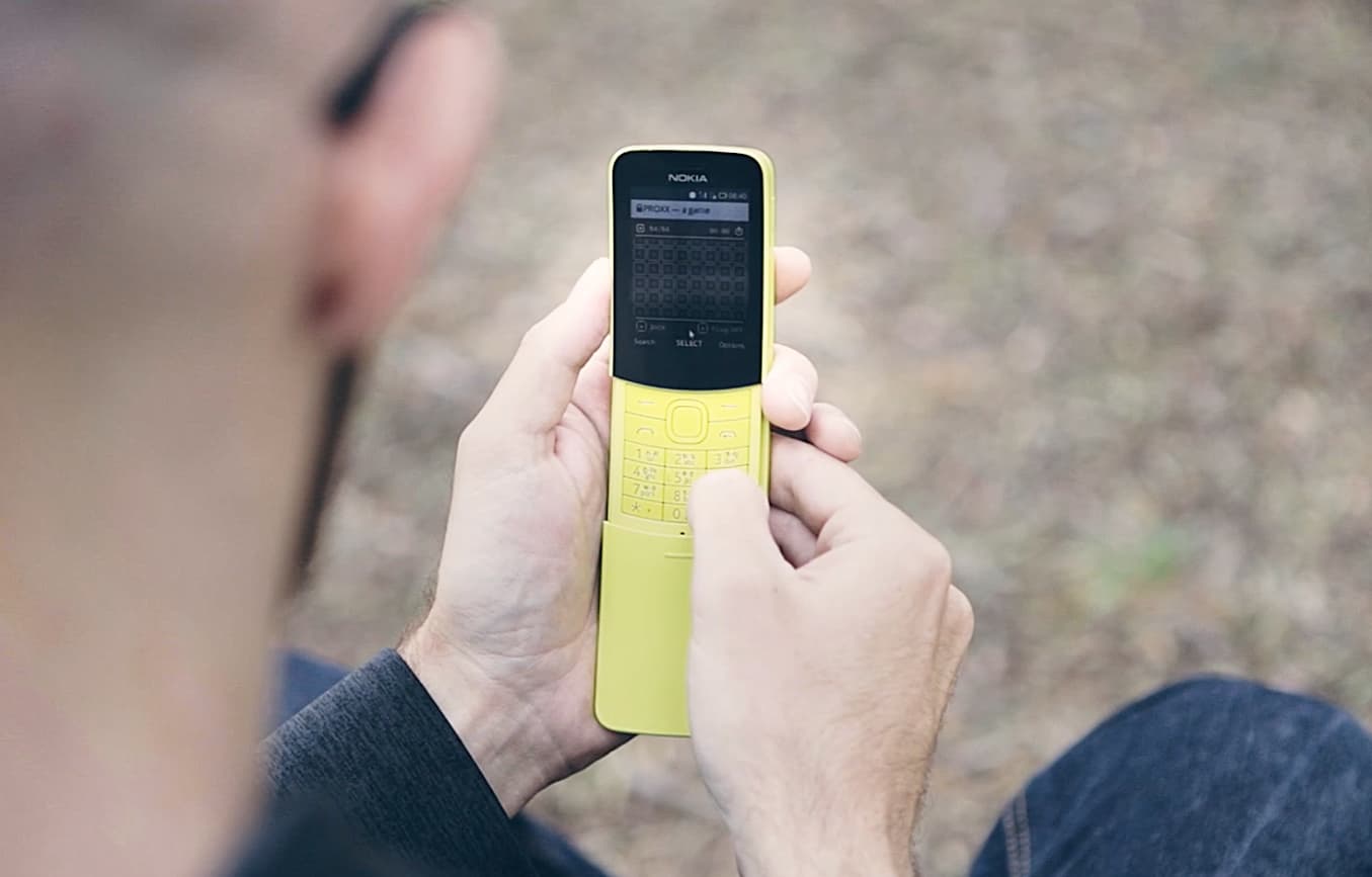 Ein Mann, der „PROXX“ auf einem gelben Feature-Phone spielt