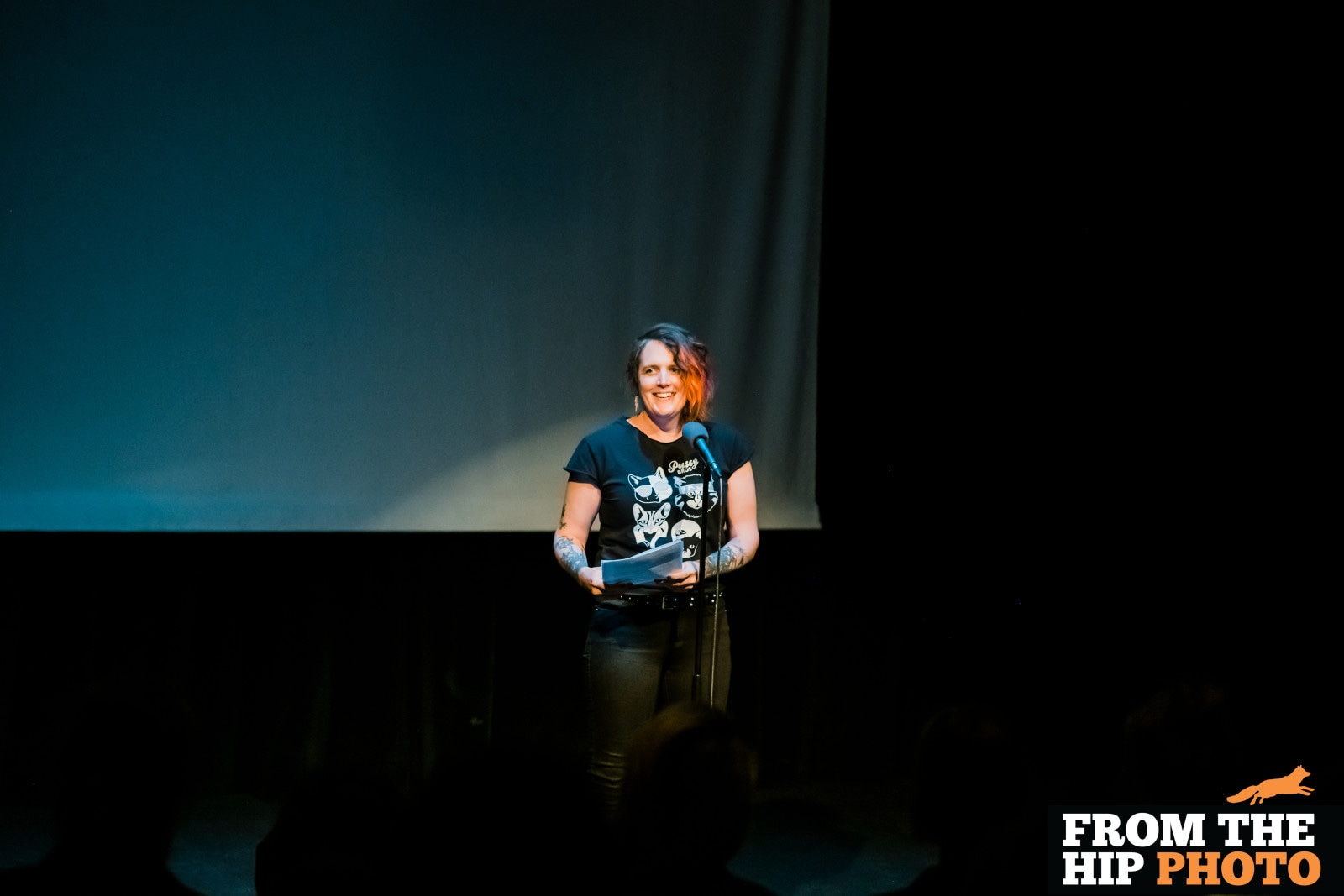 Miriam onstage, smiling, lit by a spotlight.